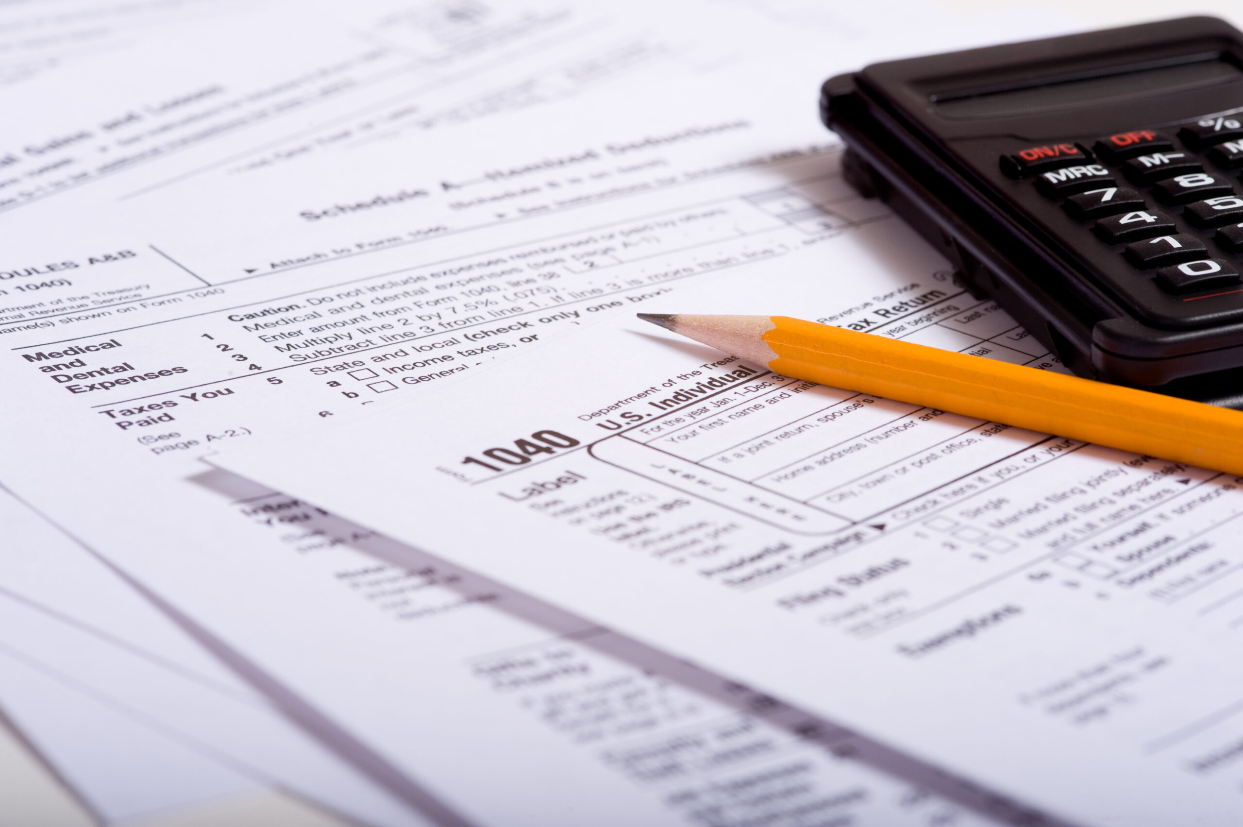 Tax prepaation items including a pencil, calculator and tax forms